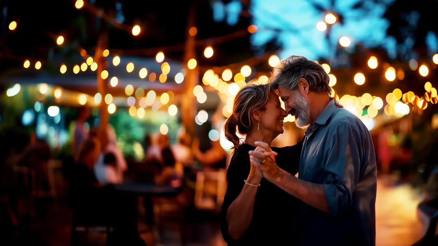 Couple dancing outside, with blurry warm lights in the background.